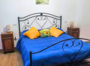 Camera accogliente con letto blu e cuscini vivaci, atmosfera calda e invitante.