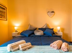 Camera accogliente con letto blu, luci soffuse e asciugamani arrotolati.