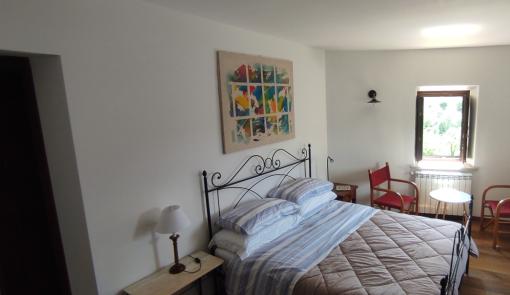 Camera accogliente con letto matrimoniale e arte colorata alle pareti.