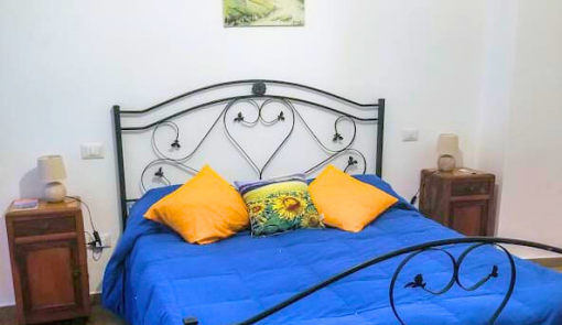 Camera accogliente con letto blu e cuscini vivaci, atmosfera calda e invitante.